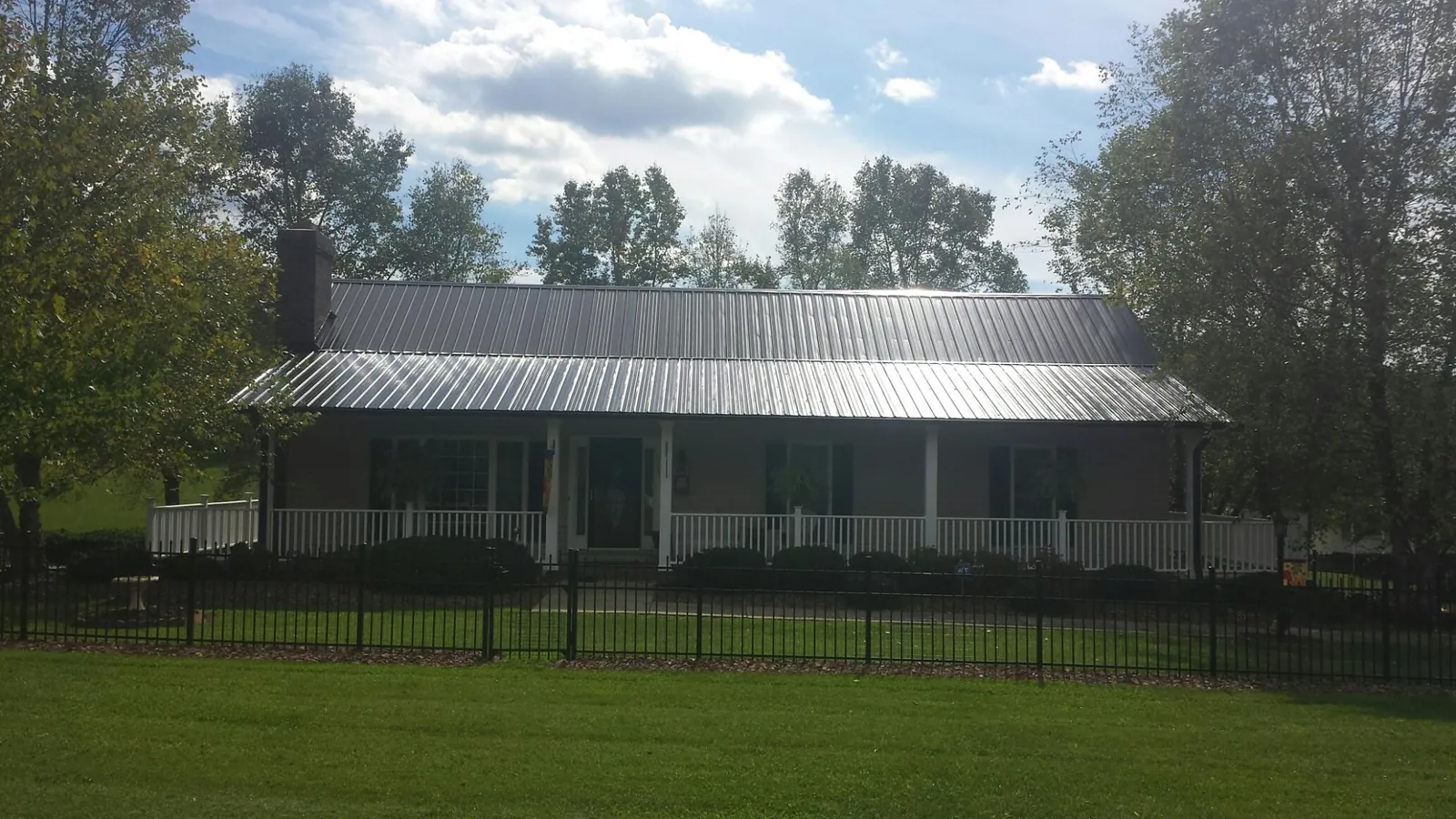 Gray metal roof on a brick ranch with a full width front porch — Gutter Guard Installation work by our crew in Dunkirk