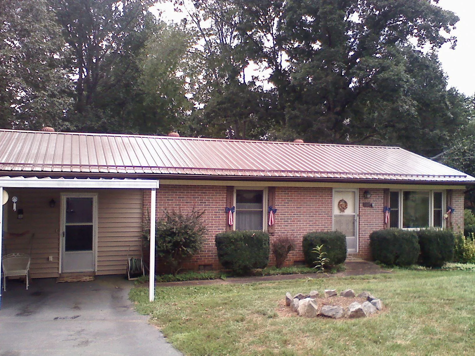 Bronze metal roof and carport on a brick ranch home — Roof Repair work by our crew in Dunkirk