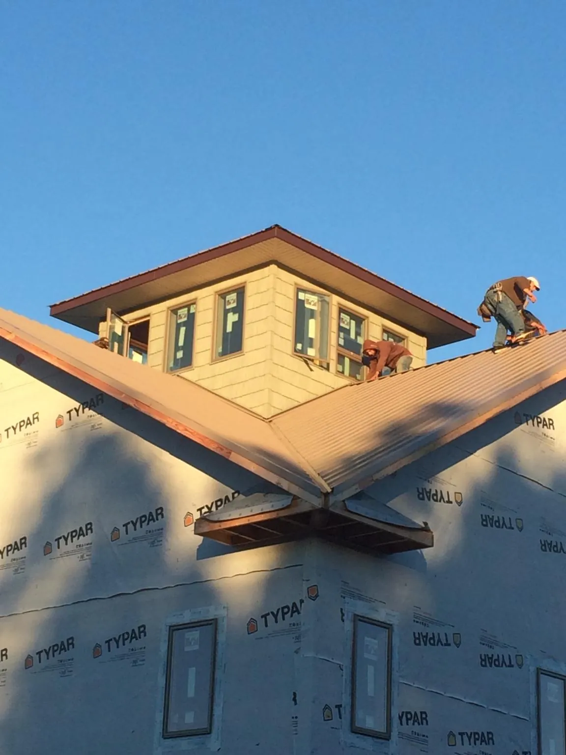 Roofers working around a rooftop cupola on a new metal roof at sunset — Roof Waterproofing in Dunkirk by Roofing Brothers